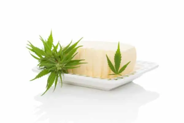 Cannabutter on white plate with cannabis leaves, make cannabutter