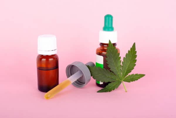 cannabis tinctures with cannabis leaf on pink