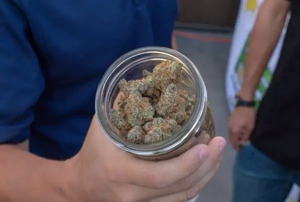 guy holding a jar of cannabis, marijuana prices and what you should know