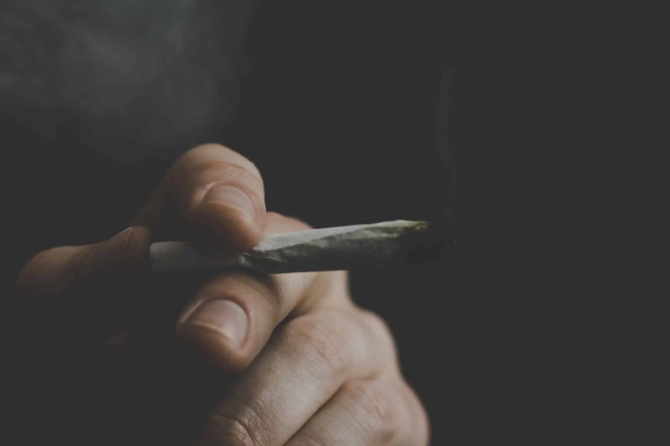 How Cannabis Legalization Affects the Black Market. Hand holding a joint.