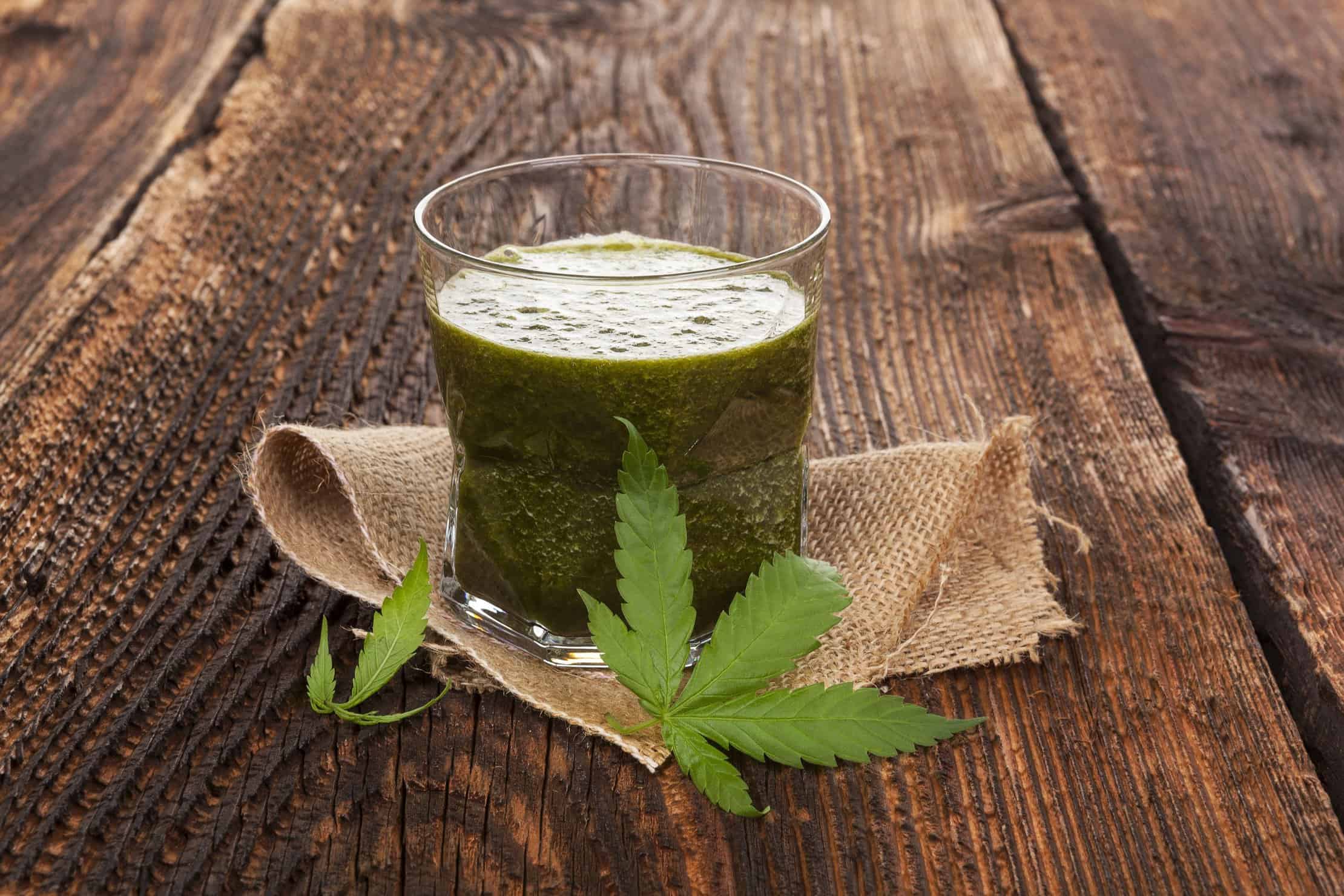 Discover the Benefits of Marijuana Juicing. Cup of juice on wooden table.