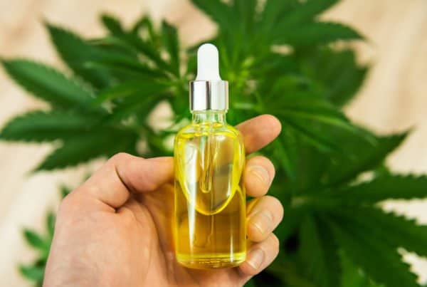 a hand holding cbd oil in a tincture, how to make cbd oil
