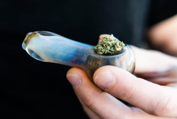 hand holding a bong with cannabis in it, cannabis pothead users
