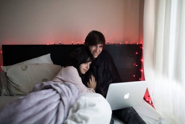 Couple watching Pot documentaries on Netflix in bed on an Apple laptop