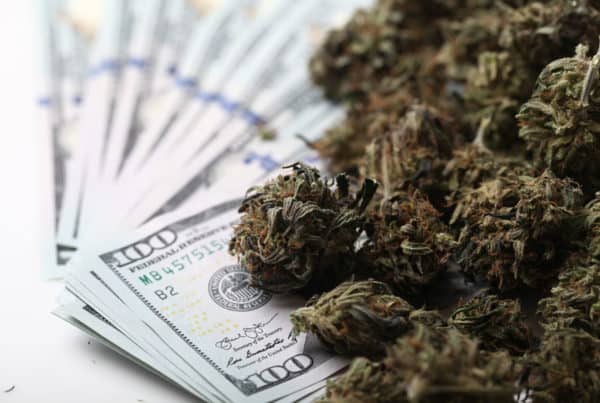 Oklahoma Makes Record Revenue With Marijuana and cash on a white background.