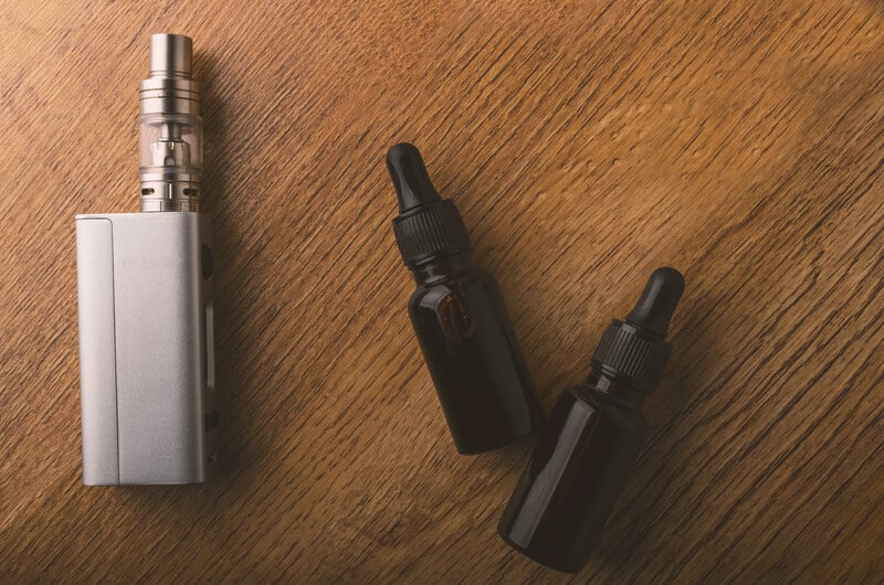 Best Vape shops in NYC with a vape pen and vape juice on wood surface.
