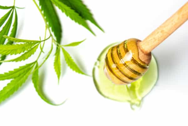 Hemp honey sticks oil bowl of honey with a marijuana leaf.