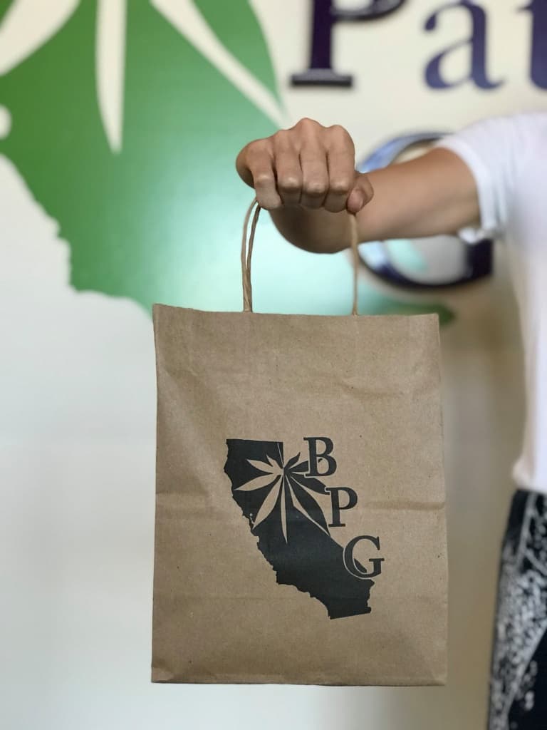 Berkeley Patient Group paper bag with logo on it.