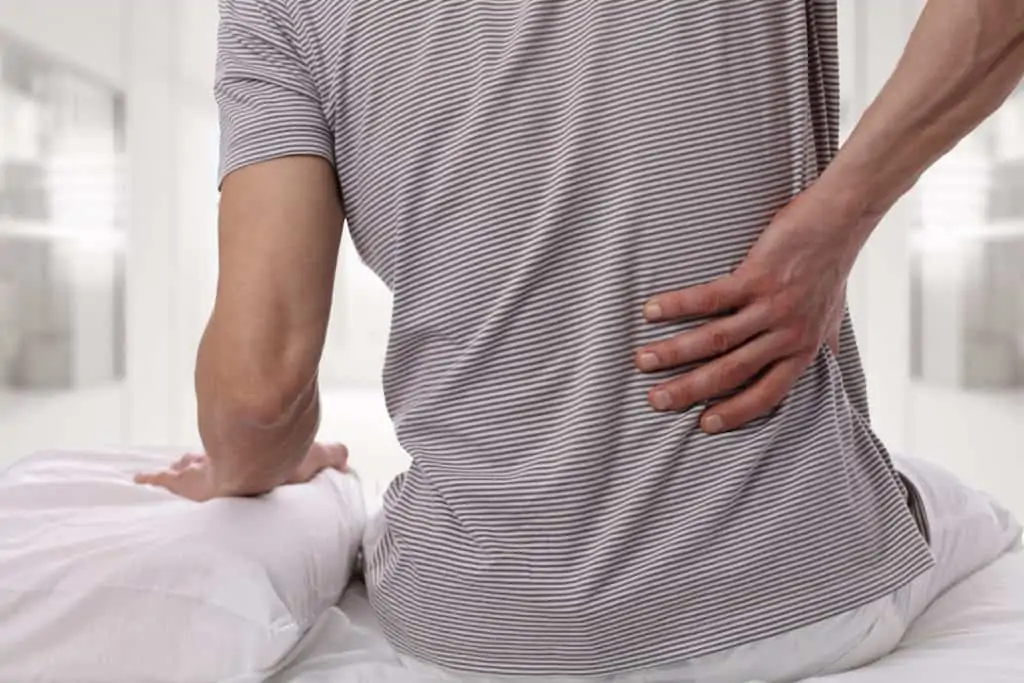 man holding his back in pain, is sativa or indica better for back pain