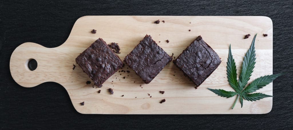 Dark Chocolate Homemade Brownies Infused with Medical Cannabis, with Marijuana leaf on wooden tray, weed recipes