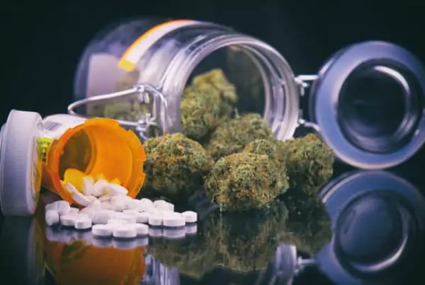 cannabis flower in a glass jar and prescription pills, medical marijuana for anxiety