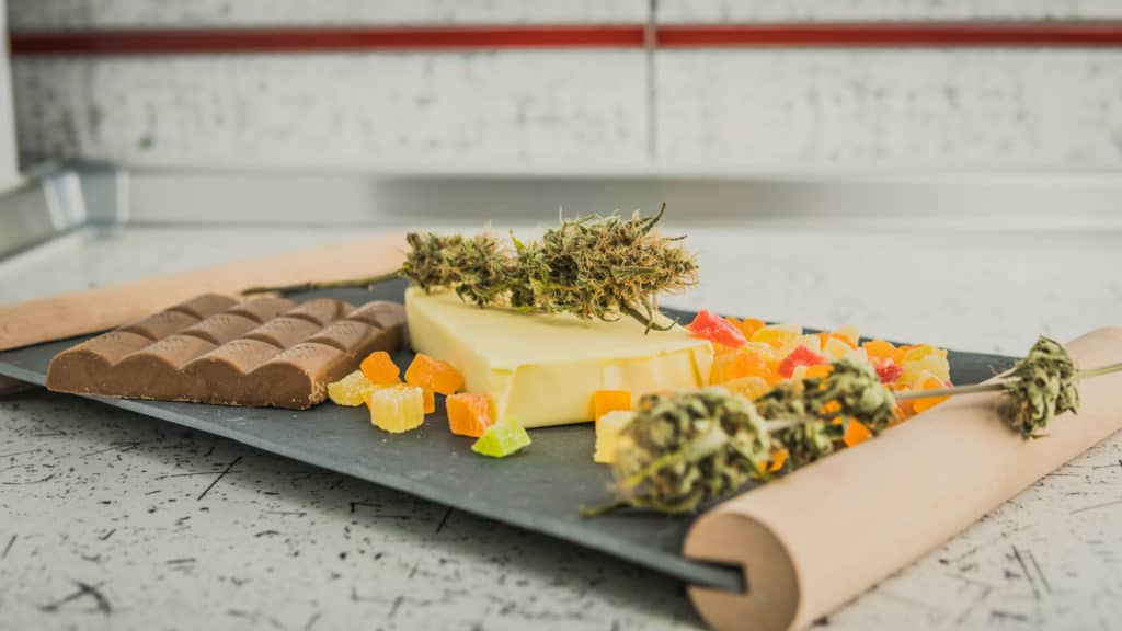 gummies and chocolates on cutting board with cannabis