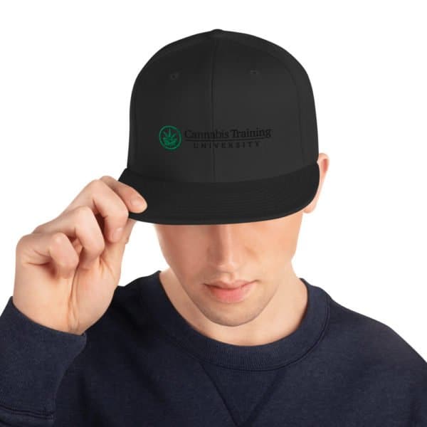 A man wearing a black Snapback Cannabis Training University hat.