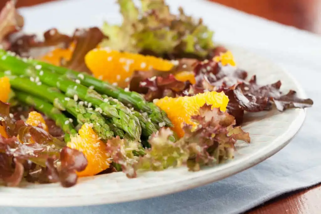 lettuce and mandarins on a white plate with hemp seeds