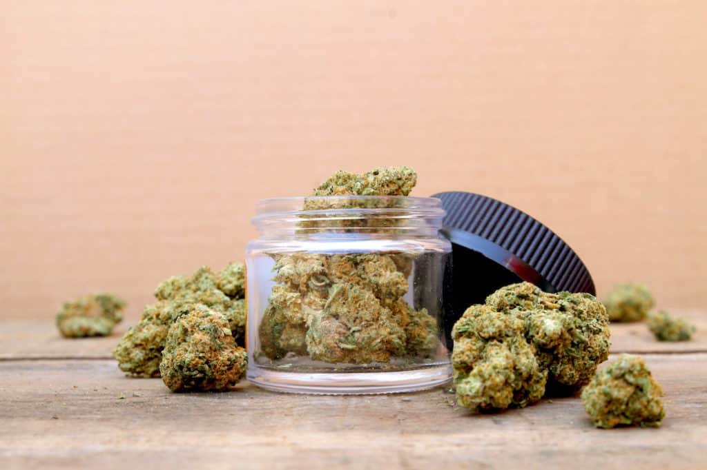 cannabis buds in a jar and on a table, what is an eighth of weed