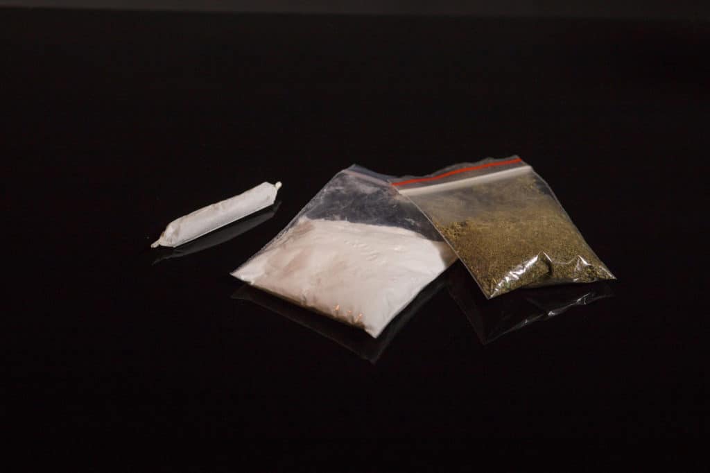 bag of white powder, joint and bag of weed next to each other, cocaine and marijuana