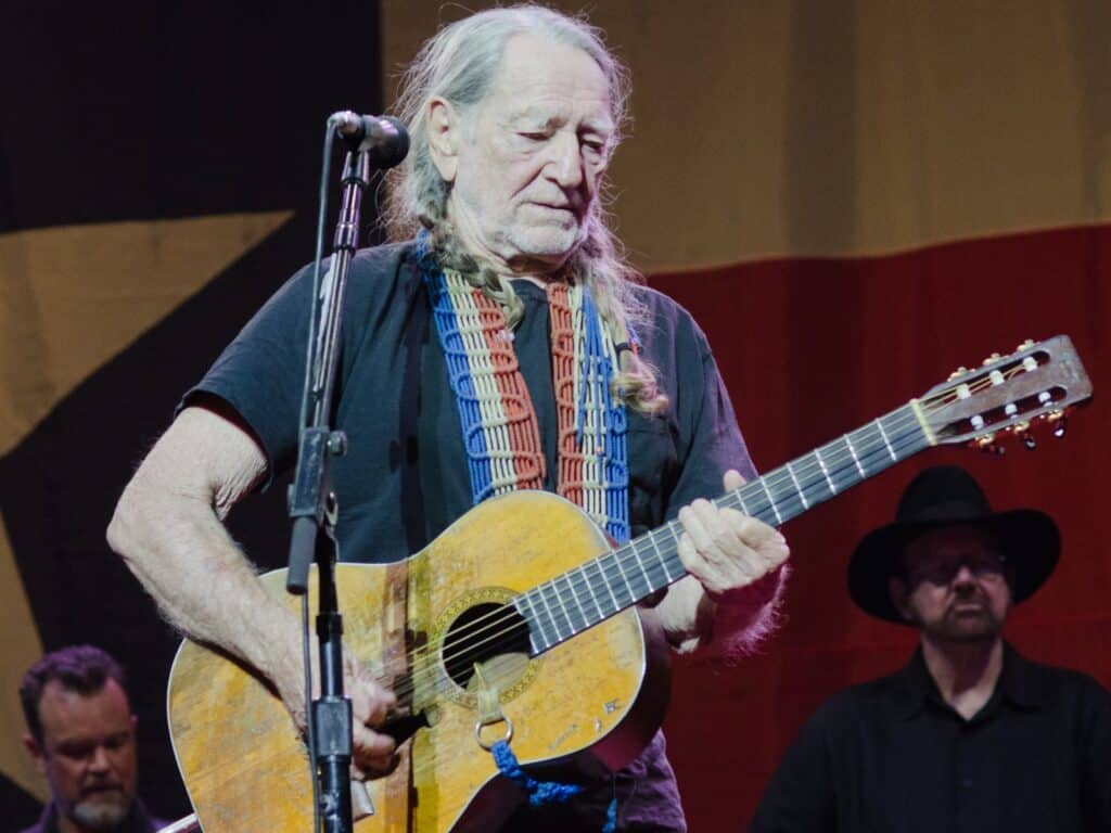 Famous People That Smoke Weed : 2025 Updates 2 Willie Nelson, playing guitar live, one of the most well known famous people that smoke weed.