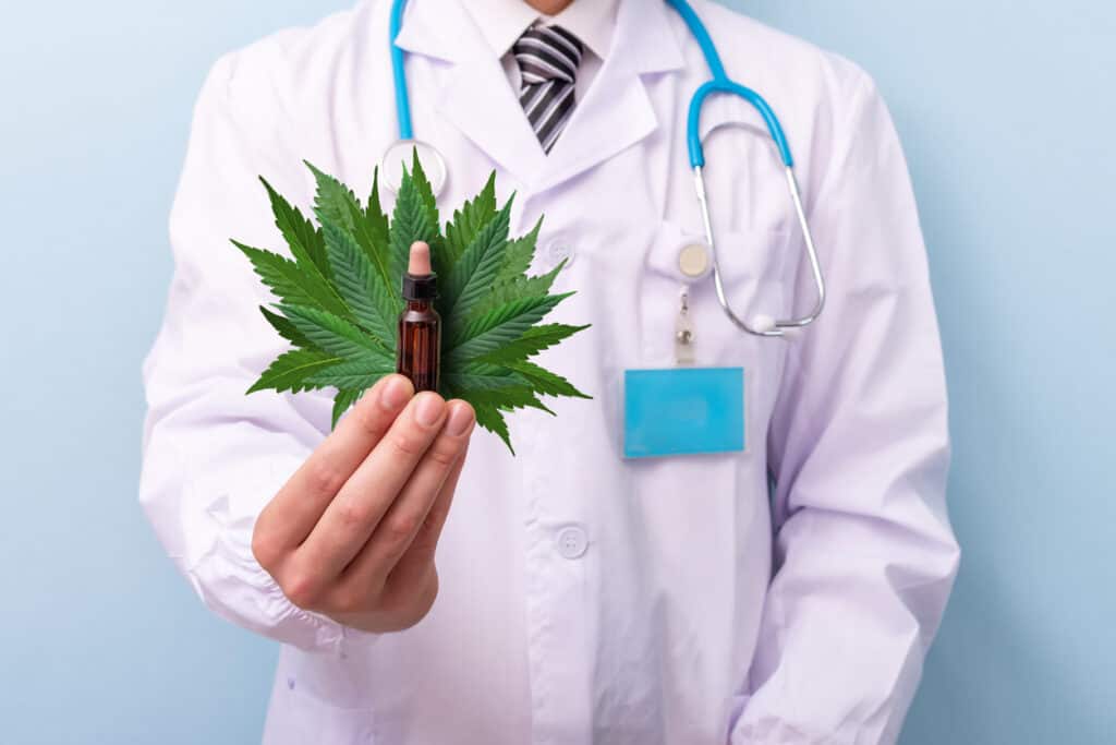 Becoming a cannabis patient in Colorado. Doctor holding a cannabis leaf and a cbd tincture bottle/ 